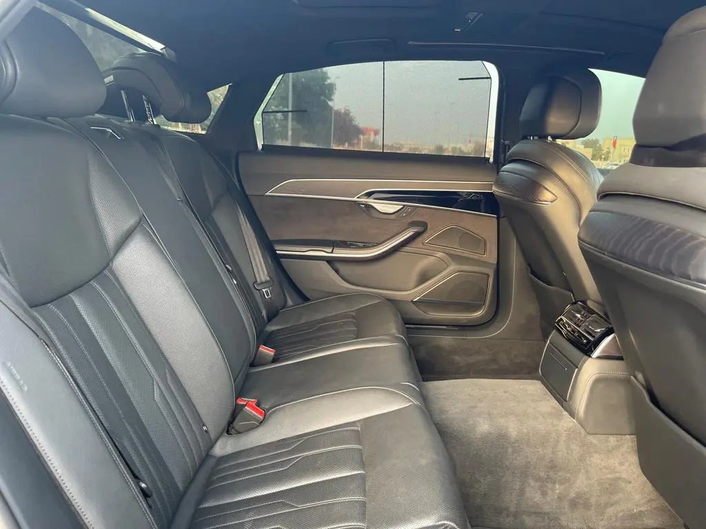 Audi A8 luxury rental cruising on a Dubai highway, showcasing its powerful stance and dynamic design.