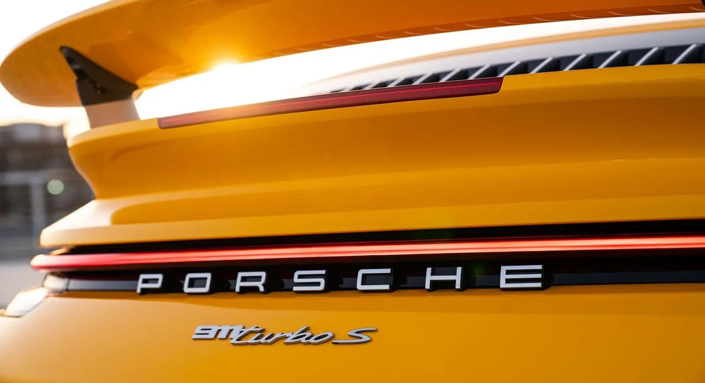 Full view of Porsche 911 Turbo S parked by Dubai skyline, ultimate sports car rental experience.