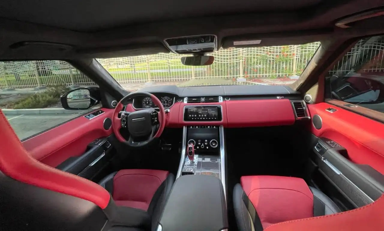 Rear angle of a Range Rover SVR under Dubai's skyline, focusing on its sporty design and superior exhaust system for luxury rentals.