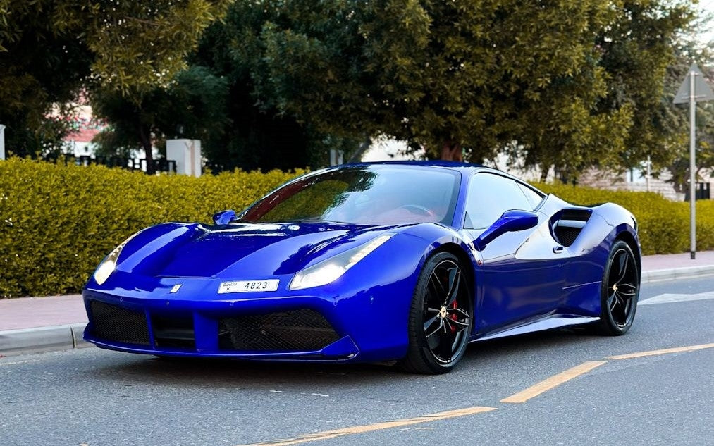Luxury red Ferrari 488 sports car side view, ready for rent in Dubai, showcasing sleek design.