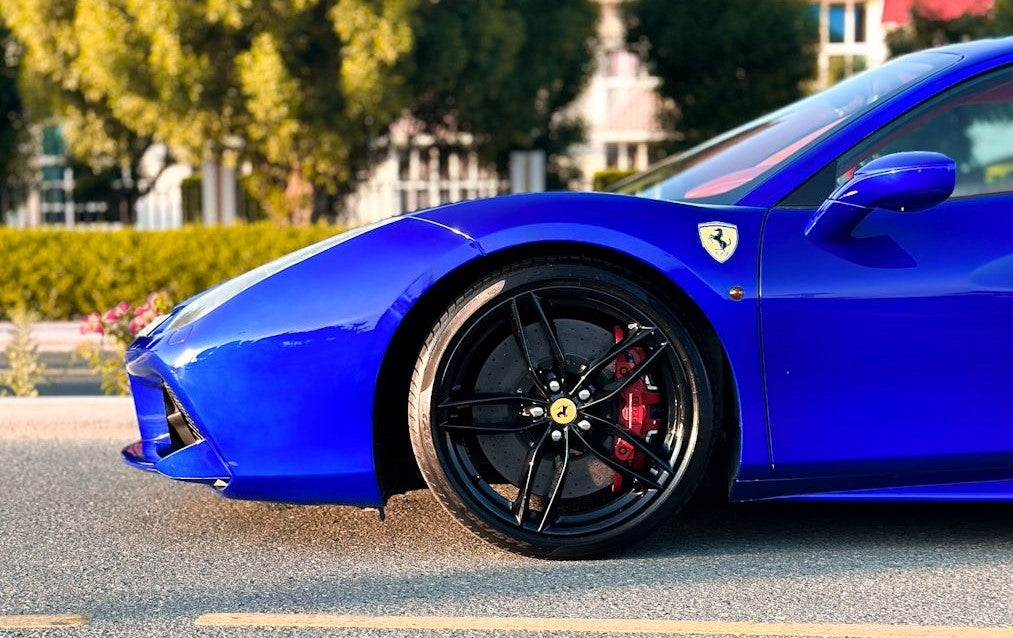 Ferrari 488 parked by Dubai skyline, epitomizing luxury sports car rental elegance.