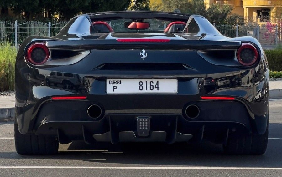 Rear angle of a Ferrari 488 Spyder sports car rental parked in Dubai, displaying its powerful exhaust and stylish taillights.