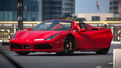 Red Ferrari 488 Spyder luxury sports car for rent in Dubai, showcasing its sleek profile and aerodynamic design.