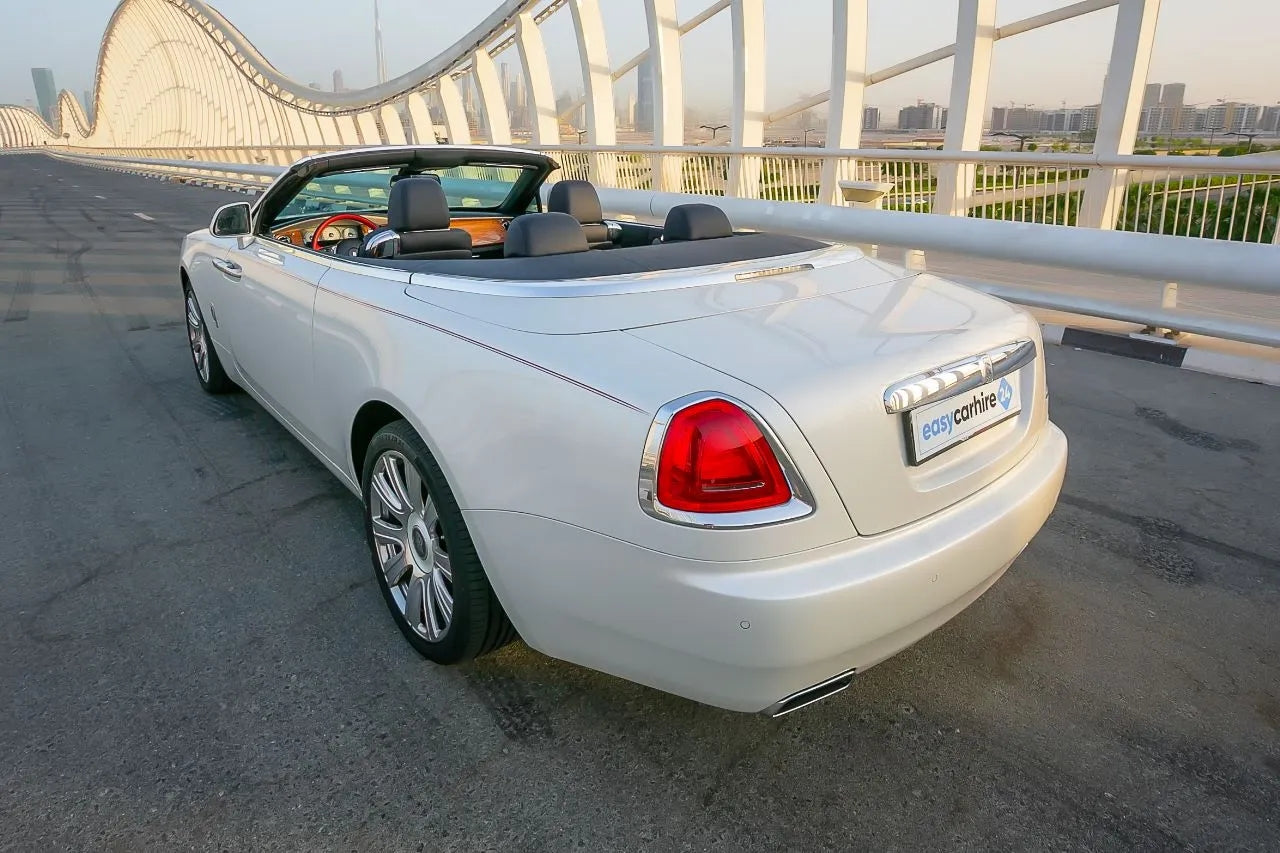 Rear angle of a Rolls Royce Dawn, emphasizing the iconic taillights and convertible top, perfect for Dubai rentals.